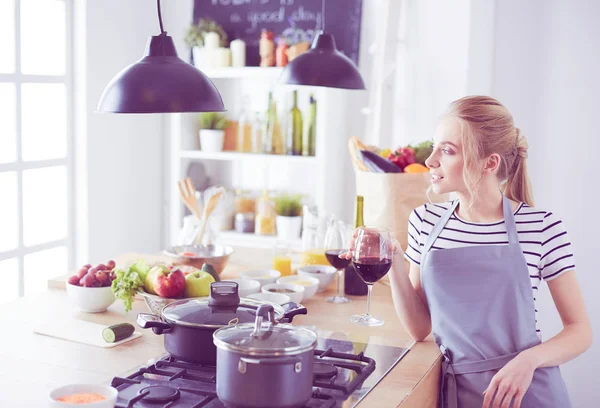 Mulher bonita bebendo um pouco de vinho em casa na cozinha — Fotografia de Stock