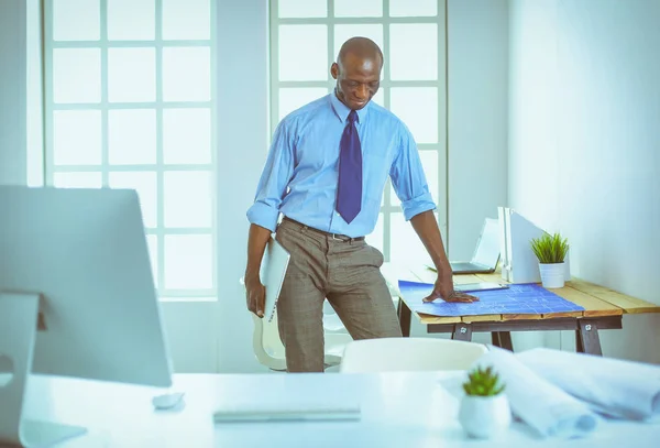 Arquiteto afro-americano trabalhando com computador e plantas no escritório — Fotografia de Stock