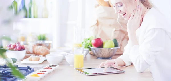 Bella giovane donna utilizzando un tablet digitale in cucina — Foto Stock