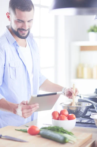 Dijital tablet ve yemek pişirme tarifine uyan bir adam evdeki mutfakta lezzetli ve sağlıklı yemekler pişiriyor. — Stok fotoğraf