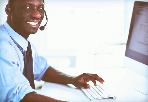 Hombre de negocios afroamericano con auriculares trabajando en su computadora portátil — Foto de Stock
