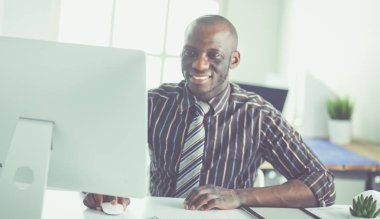 Yakışıklı Afro Amerikalı işadamı Klasik takım elbiseli bir dizüstü bilgisayar kullanarak ve ofiste çalışırken gülümseyen