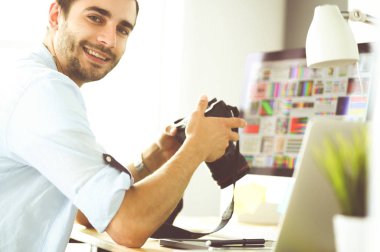 İnternette çalışırken bilgisayarın ve dizüstü bilgisayarın önünde grafik stüdyosunda oturan genç tasarımcının portresi