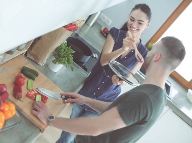 Bir çift evdeki mutfaklarında birlikte yemek pişiriyor.