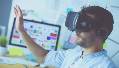 Genç erkek yazılım programcısı ofiste üç boyutlu sanal gerçeklik gözlükleriyle yeni bir uygulama test ediyor..