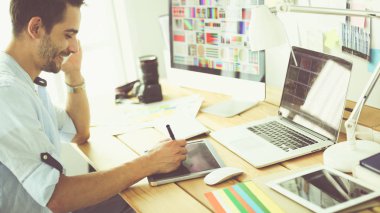 İnternette çalışırken bilgisayarın ve dizüstü bilgisayarın önünde grafik stüdyosunda oturan genç tasarımcının portresi