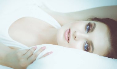 Genç ve güzel bir kadın yatakta yatıyor.