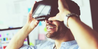 Genç erkek yazılım programcısı ofiste üç boyutlu sanal gerçeklik gözlükleriyle yeni bir uygulama test ediyor..