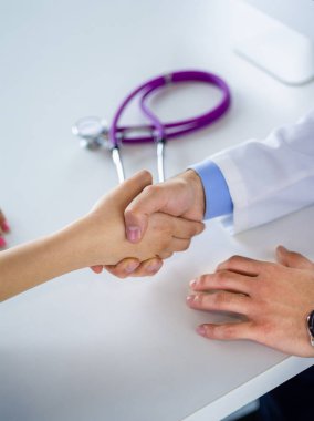 Doktor masadaki hastaya el sıkışıyor.