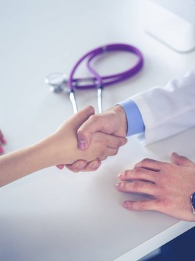 Doktor masadaki hastaya el sıkışıyor.