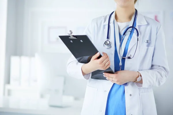 Smiling female doctor with a folder in uniform standing — Stok Foto