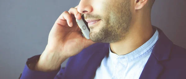 Atractivo joven con teléfono inteligente en el fondo de color —  Fotos de Stock