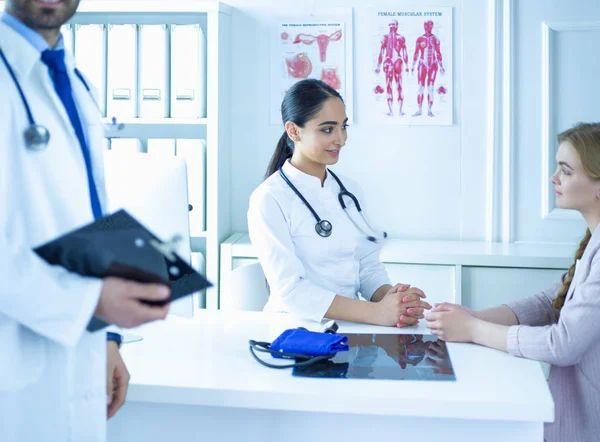 Närbild av läkare och patient sitter vid skrivbordet nära fönstret på sjukhuset — Stockfoto