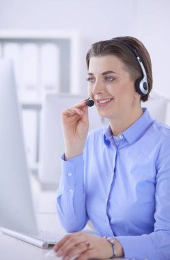 Ofisinde kulaklık takmış, telefon operatörü olarak çalışan ciddi ve güzel bir genç kadın.