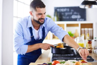 Adam ev mutfağında lezzetli ve sağlıklı yemekler hazırlıyor.