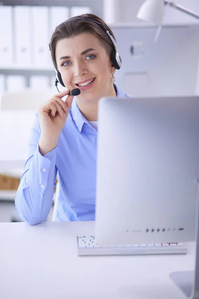 Ernsthafte hübsche junge Frau arbeitet als Telefonistin mit Headset im Büro — Stockfoto