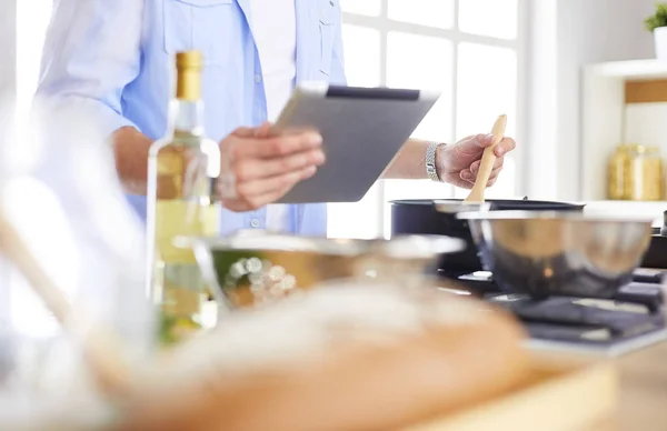 Hombre siguiendo la receta en la tableta digital y cocinar comida sabrosa y saludable en la cocina en casa — Foto de Stock