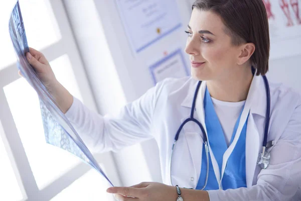 Portrait of doctor sitting in office holding xray image, working on computer — Stock Photo, Image