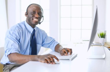 Kulaklıklı Afro-Amerikan işadamı laptopuyla çalışıyor.