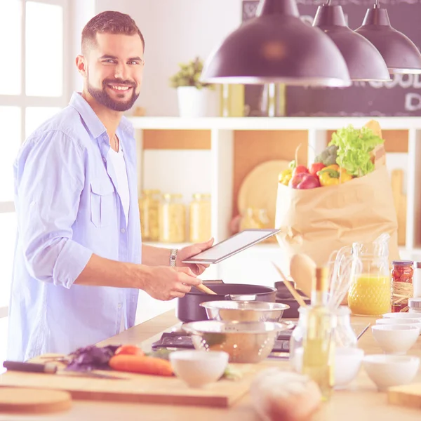 Man volgens recept op digitale tablet en lekker en gezond koken in de keuken thuis — Stockfoto