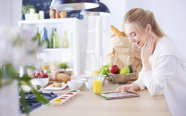 Bella giovane donna utilizzando un tablet digitale in cucina — Foto Stock