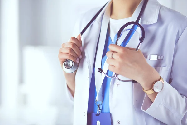 Retrato de una joven doctora con una bata blanca de pie en el hospital — Foto de Stock