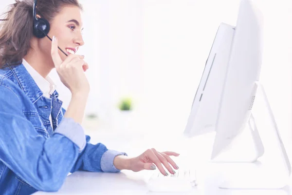 Feliz encantadora joven sentada y trabajando con el ordenador portátil con auriculares en la oficina —  Fotos de Stock