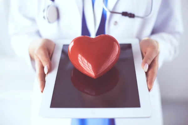 Medico femminile con stetoscopio che tiene il cuore, su sfondo chiaro — Foto Stock