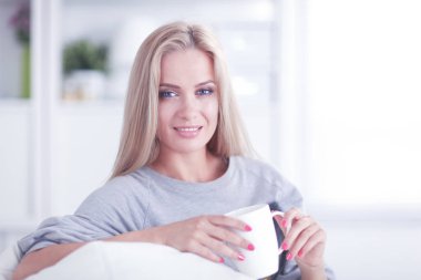 Ellerini içine ile kanepede oturan ve onun önünde göründüğü gülümseyen kadın