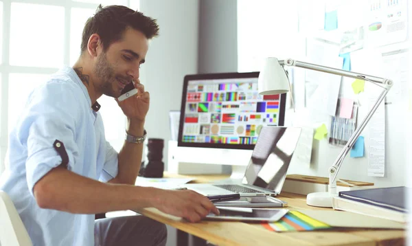 Porträt eines jungen Designers, der im Grafikstudio vor Laptop und Computer sitzt, während er online arbeitet. — Stockfoto