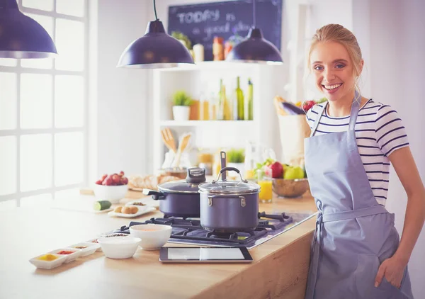 Mujer joven de pie cerca de escritorio en la cocina —  Fotos de Stock