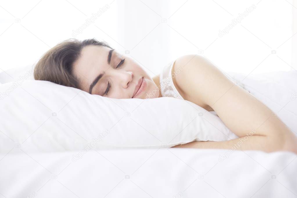 Pretty woman lying down on her bed at home