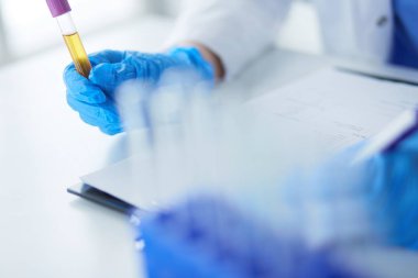 Kadın araştırmacı, beyaz arka planda izole edilmiş ilaç şişeleri ve mataralarla çevrili.