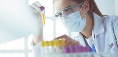 Modern laboratuvar veya hastanede plastik tıbbi tüplerle çalışan araştırmacı, doktor, bilim adamı veya laboratuvar asistanı