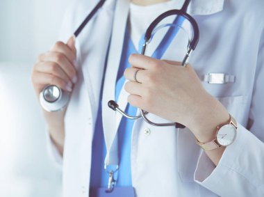 Kadın doktor hastanede steteskopla dikiliyor.