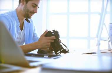 İnternette çalışırken bilgisayarın ve dizüstü bilgisayarın önünde grafik stüdyosunda oturan genç tasarımcının portresi.