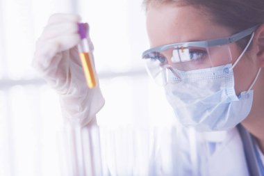 Modern laboratuvar veya hastanede plastik tıbbi tüplerle çalışan araştırmacı, doktor, bilim adamı veya laboratuvar asistanı