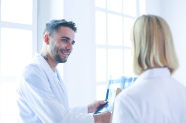 Yakışıklı doktor genç bayan doktorla konuşuyor ve ofisinde otururken notlar alıyor..