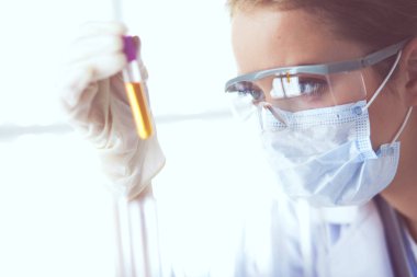 Modern laboratuvar veya hastanede plastik tıbbi tüplerle çalışan araştırmacı, doktor, bilim adamı veya laboratuvar asistanı