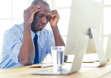 Kulaklıklı Afro-Amerikan işadamı laptopuyla çalışıyor.