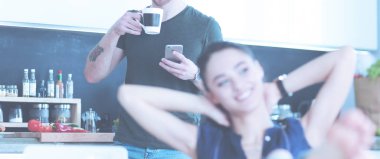 Mutlu çift mutfakta oturmuş smartphone kullanarak