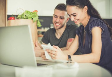 Çift evde mutfak içinde laptop ile onların fatura ödeme