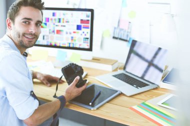 İnternette çalışırken bilgisayarın ve dizüstü bilgisayarın önünde grafik stüdyosunda oturan genç tasarımcının portresi.