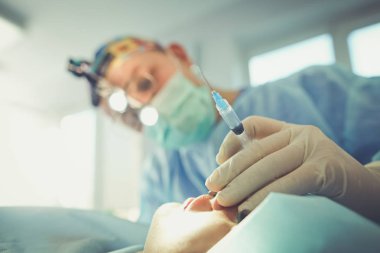 Ameliyat odasında arka planda erkek cerrah var.