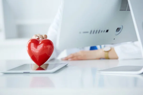 Ärztin mit Stethoskop, das Herz hält, auf hellem Hintergrund — Stockfoto