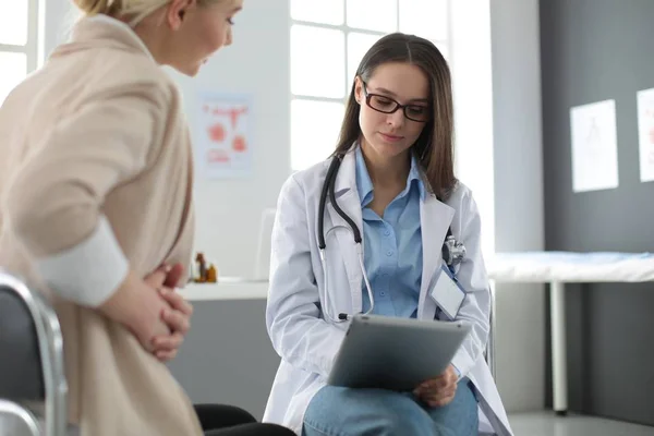 Doktorn och patienten diskuterar något när de sitter vid bordet. Medicin och hälsovård — Stockfoto