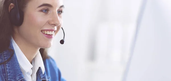 Retrato de una hermosa mujer de negocios trabajando en su escritorio con auriculares y portátil — Foto de Stock