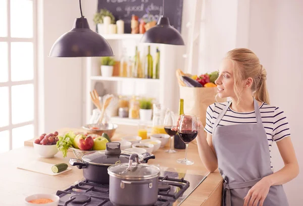 Mulher bonita bebendo um pouco de vinho em casa na cozinha — Fotografia de Stock