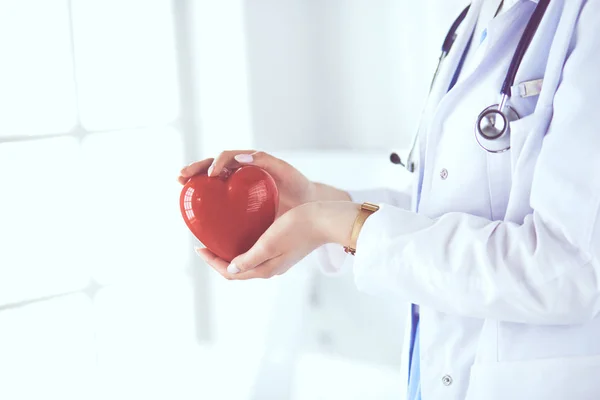 Médica com estetoscópio segurando coração, em fundo claro — Fotografia de Stock