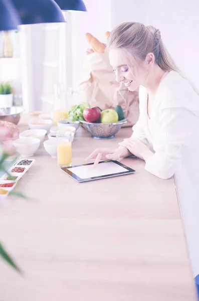 Schöne junge Frau mit einem digitalen Tablet in der Küche — Stockfoto